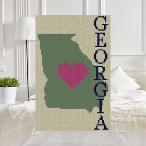 May include: A green outline of the state of Georgia with a pink heart in the center. The word "GEORGIA" is spelled vertically in navy blue letters to the right of the state outline.