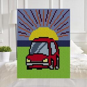 May include: A red car driving into a pixelated sunset with a yellow sun and orange rays. The car is on a green field with a blue sky in the background.