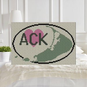 May include: A cross-stitch design of the island of Nantucket, Massachusetts, with the letters "ACK" and a pink heart in the center. The design is surrounded by a black oval.