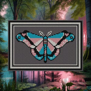 Könnte beinhalten: Ein gerahmtes Kreuzstich-Design eines Schmetterlings mit blauen, rosa und weißen Flügeln. Der Schmetterling ist vor einem grauen Hintergrund platziert.