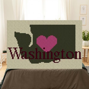 May include: A crochet pattern featuring the outline of the state of Washington with a pink heart in the center and the word "Washington" below. The pattern is on a beige background.