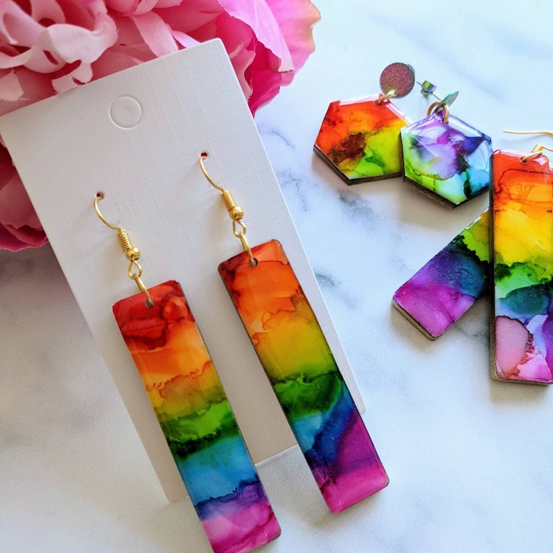 Rainbow rectangle earrings. Drop 6cm. 1.5cm wide. Gold or silver. Hand painted ink painting mounted onto wooden shapes. Resin coating. Hypoallergenic and lightweight.