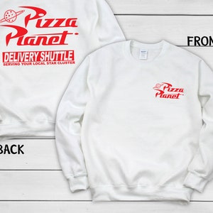 May include: White sweatshirt with red "Pizza Planet" logo and text. The front features a small logo, while the back displays the full logo with "Delivery Shuttle" and "Serving Your Local Star Cluster."