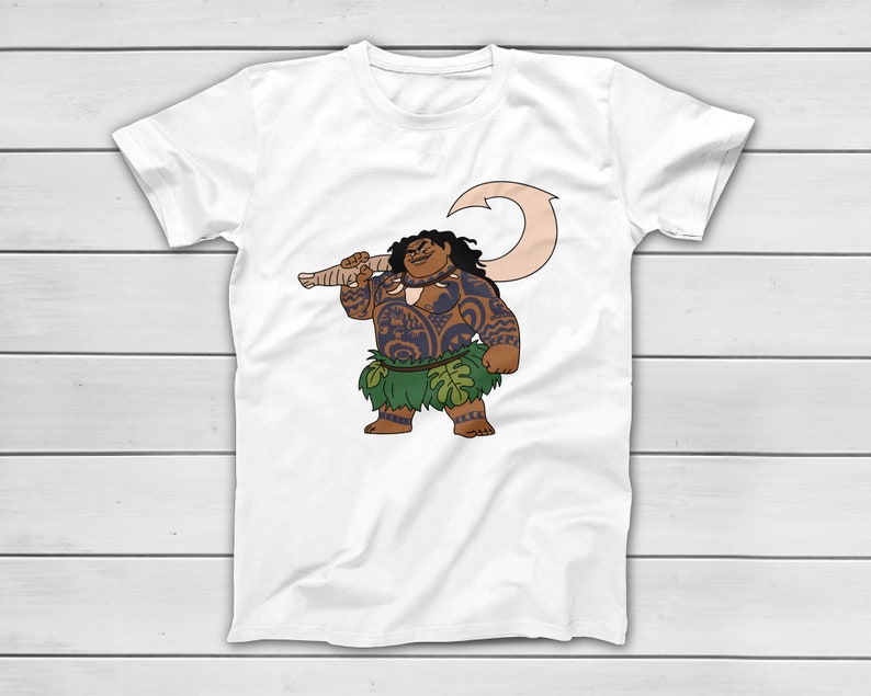 Puede incluir: Camiseta blanca con una ilustraci&oacute;n de dibujos animados de un personaje polinesio. El personaje tiene tatuajes, una falda de hierba verde y un gran gancho. El personaje sonr&iacute;e y sostiene el gancho sobre su hombro. El dise&ntilde;o est&aacute; centrado en la camiseta.