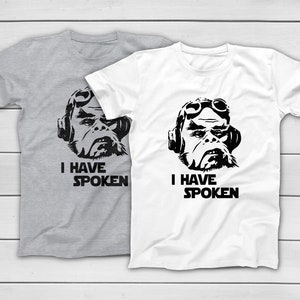 May include: Two t-shirts, one grey and one white, each with a black graphic of a character wearing goggles and headphones. The text "I HAVE SPOKEN" is printed below the graphic.