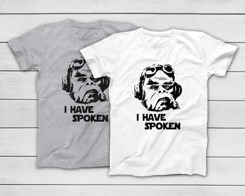 May include: Two t-shirts, one grey and one white, each with a black graphic of a character wearing goggles and headphones. The text "I HAVE SPOKEN" is printed below the graphic.