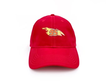 May include: A red baseball cap with a curved brim. The cap features an embroidered design of a flame with the number "95" in yellow and orange. The cap is made of a soft fabric and has a structured fit.