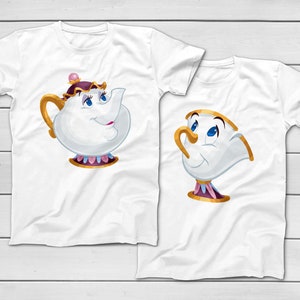 May include: Two white t-shirts featuring cartoon characters from Beauty and the Beast. One shirt displays a teapot with a gold handle and a purple hat. The other shirt shows a teacup with a gold handle and a pink and gold base.