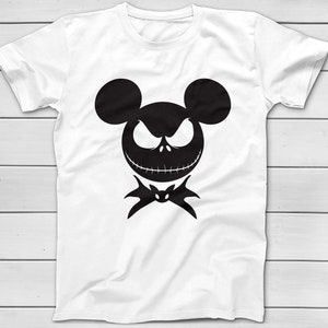 May include: White t-shirt featuring a black silhouette of a character's face with mouse ears, an angry expression, and a bat-shaped bow tie. The design is centered on the shirt, which has short sleeves and a crew neck.