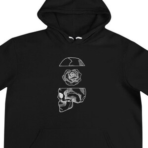 Op de afbeelding: Zwarte hoodie met een witte afbeelding van een schedel met een roos in zijn hoofd.
