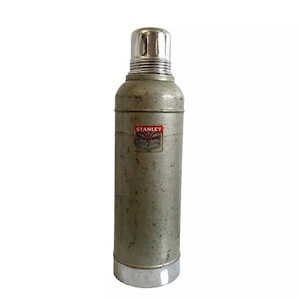 May include: A vintage silver Stanley flask with a red and white label that says "Stanley Vacuum Bottle".