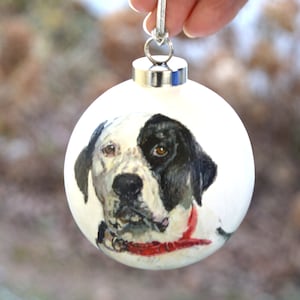 Pode incluir: Ornamento de Natal branco com um retrato pintado &agrave; m&atilde;o de um c&atilde;o preto e branco usando uma bandana vermelha.