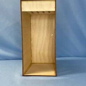 May include: A wooden box with a removable top and a series of small holes in the top. The box is empty and has a light brown finish.