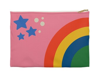 May include: A rectangular pink zippered pouch with a colorful design. The design features a rainbow in red, orange, yellow, blue, and green. Three blue stars and three white circles are on the pink background. The zipper is gold.