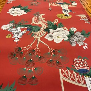 May include: A red wallpaper featuring a repeating pattern of white and grey peonies, stylized green pine trees, and figures holding umbrellas. The design includes architectural elements and text that reads MADE IN U.S.A. and STRIP MATCH.
