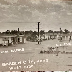 May include: A vintage black and white postcard showing the Broadview Cabins and a Conoco gas station in Garden City, Kansas. The scene features a service station with fuel pumps, a row of small cabins, utility poles, and text reading Broadview Cabins, A.T. Faeth, and Garden City, Kans. West Side.