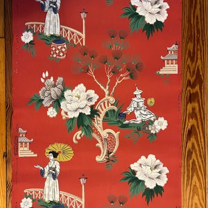 May include: A roll of wallpaper with a vibrant red background featuring a repeating pattern of figures holding yellow umbrellas, white pagodas, large white peony flowers, and green pine trees. The text "MADE IN U.S.A." is printed on the side.