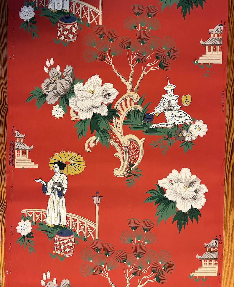 May include: A roll of wallpaper with a red background featuring a repeating pattern of white peonies, green pine trees, pagodas, and figures in traditional clothing. Text on the edges includes "MADE IN U.S.A.", "MATCH", "LOT", and "TOP".