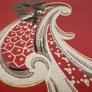 May include: A textured red surface featuring a painted paisley motif in shades of beige, brown, and dark green. The design includes a honeycomb pattern filled with gold dots, accented by gold outlines and a small green leafy sprig at the top.
