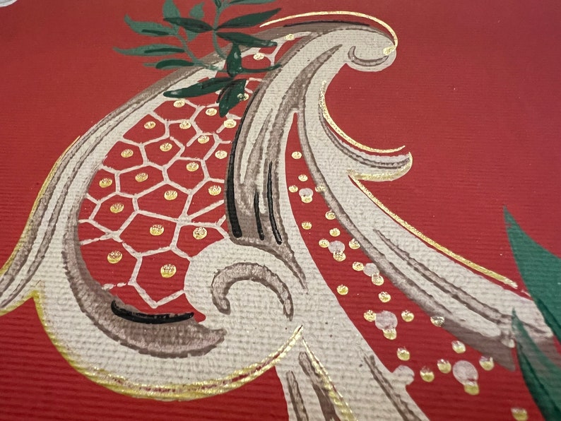May include: A textured red surface featuring a painted paisley motif in shades of beige, brown, and dark green. The design includes a honeycomb pattern filled with gold dots, accented by gold outlines and a small green leafy sprig at the top.