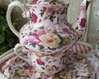Beautiful rose adorned porcelain teapot and teacup set. This lovely pink stacking teapot and teacup has been painted with gold gilding