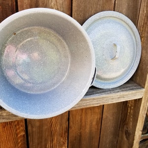 May include: A gray enamel pot with a lid. The pot has a speckled finish and a handle on the side. The lid has a handle on top.