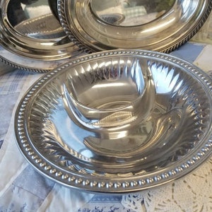 Puede incluir: Un conjunto de fuentes de plata. El juego incluye fuentes ovaladas con bordes de cuerda y una fuente dividida con un borde de cuentas. Las superficies reflectantes crean una apariencia brillante y elegante.