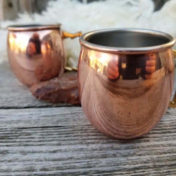 A pair of copper clad shot glass mugs . These two diminutive Moscow mule shot glasses make for fun, unusual and memorable shots.