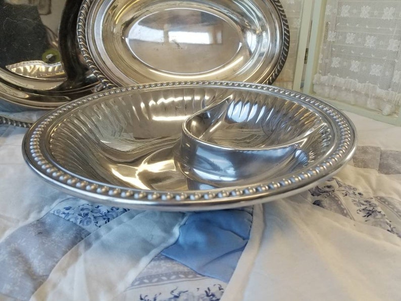 Puede incluir: Un juego de fuentes de plata. El juego incluye una fuente ovalada y una fuente dividida con un peque&ntilde;o compartimento adjunto. Los bordes de las fuentes est&aacute;n decorados con detalles de cuentas y cuerdas. Las fuentes son reflectantes.