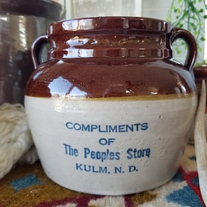 May include: A set of three ceramic mugs with a speckled, matte finish. The mugs are in shades of cream, light gray, and dark gray. Each mug has a simple, minimalist design and a rounded handle. The mugs are stacked on top of each other.