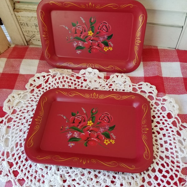 A pair of diminutive metal serving trays. With brilliant pops of color these two red vintage metal trays could be used in a myriad of ways.