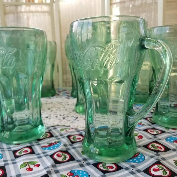 Vintage set of two heavy duty Coca-Cola glass cups. These two thick Green Glass Coke bottle glasses have that iconic look of 1950s style.