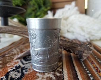 Vintage ornate German pewter shot glass. This detailed pewter vessel is adorned with German hunting, beagling elk and hunting dog motif.