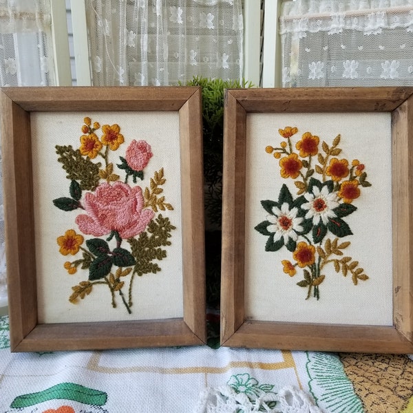 Gorgeous pair of 1970s needlepoint crewel design. This groovy pair of framed crewel work depicts a combination of sweet garden flowers.