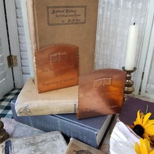 May include: Two copper bookends with an open book design. The bookends are engraved with the text "The Day of the Lord is the Beginning of Wisdom".