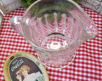 Jarra de vidrio transparente con paneles gruesos. Esta jarra vintage de vidrio grueso evoca las antiguas cafeterías o tiendas de refrescos de barrio.