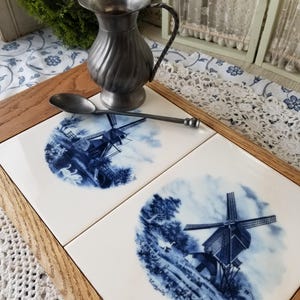 Pair of delft blue and white ceramic tile from Holland. These 2 oak framed delf tiles depict iconic counteyside Dutch windmill scenes.
