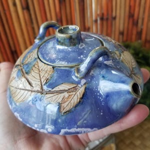 Tiny vintage Tenmoku pottery teapot with missing bamboo handle. This Leaf adorned robin's egg blue teapot was made in Malaysia.