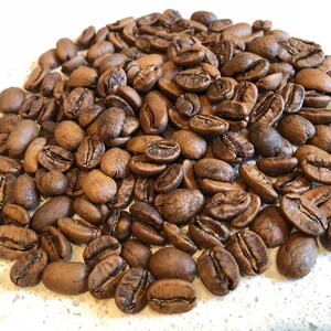 May include: A close-up image of a pile of dark brown coffee beans.
