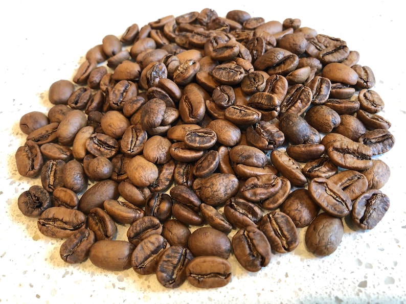 May include: A close-up image of a pile of dark brown coffee beans.