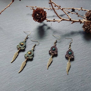 May include: A pair of green and brown beaded earrings with a feather charm. The earrings are made with a macrame technique and feature a green stone bead and a tiger's eye bead.
