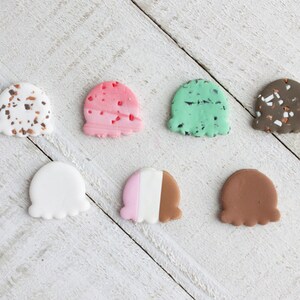 Puede incluir: Siete conos de helado en miniatura hechos de arcilla polim&eacute;rica. Los conos son de varios colores y patrones, incluyendo blanco, rosa, marr&oacute;n, verde y moteado con marr&oacute;n y blanco.