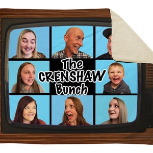 May include: A plush blanket featuring a retro television design. The screen displays a grid of smiling faces with the text "The Crenshaw Bunch" in the center. The blanket has a soft, white sherpa backing and a brown wood-grain frame.