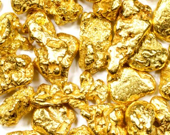 Op de afbeelding: Een close-up van een stapel goudklompjes. De klompjes zijn onregelmatig van vorm en hebben een glanzende, metalen afwerking.