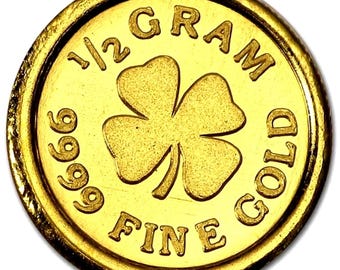 May include: A gold coin with a four-leaf clover design. The coin is stamped with "1/2 GRAM GOLD", "999 FINE". The coin has a textured edge and a bright, reflective surface.