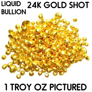 May include: A close-up of a pile of 24K gold shot, also known as liquid gold bullion. The image shows 1 troy ounce of gold shot.