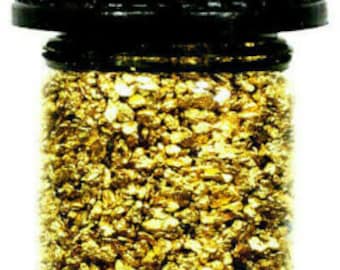 May include: A small glass jar with a black lid filled with gold flakes.