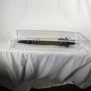 May include: A black and silver dagger with a wooden handle is displayed in a clear acrylic display case.