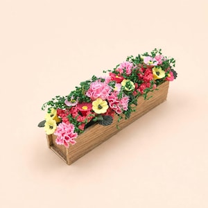 Könnte beinhalten: Eine rechteckige Holzkiste gefüllt mit einer Auswahl an bunten Blumen. Das Arrangement umfasst rosa Nelken, gelbe Gänseblümchen und rote Blumen mit grünem Laub. Die Kiste hat eine natürliche Holzmaserung.
