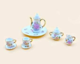 May include: A miniature porcelain tea set with floral designs. The set includes a teapot, creamer, sugar bowl, and two teacups and saucers.